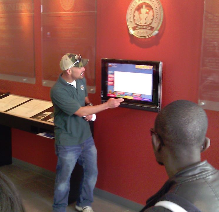 Student giving building sustainability tour points out features on dashboard