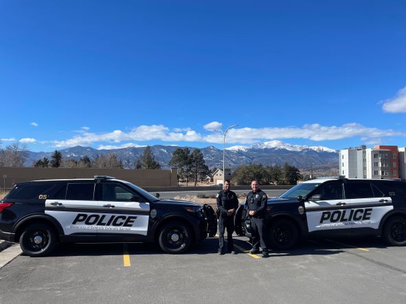 Two police officers pose with their vehicles on campus