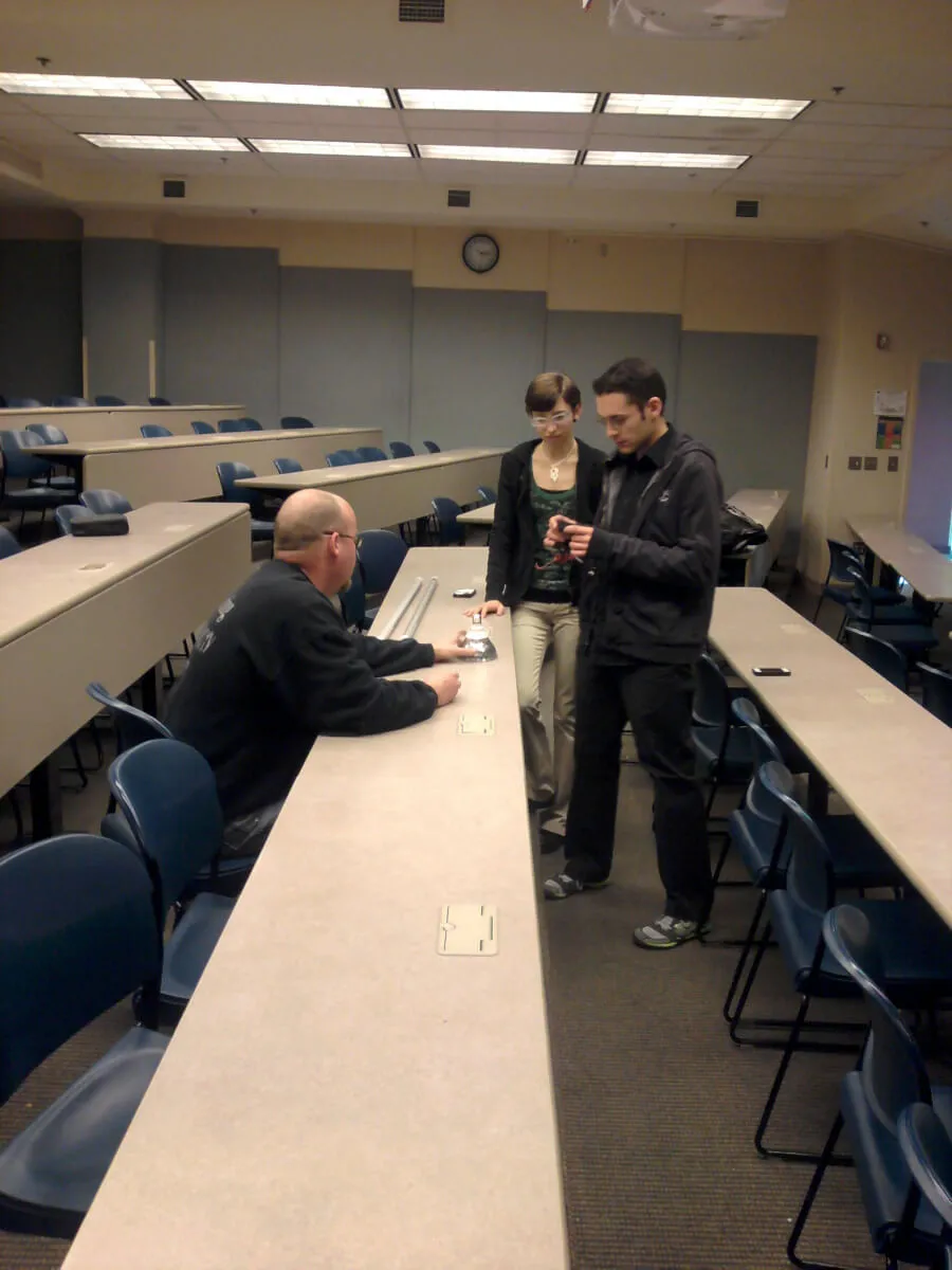 Three people in an academic classroom discussing light bulbs