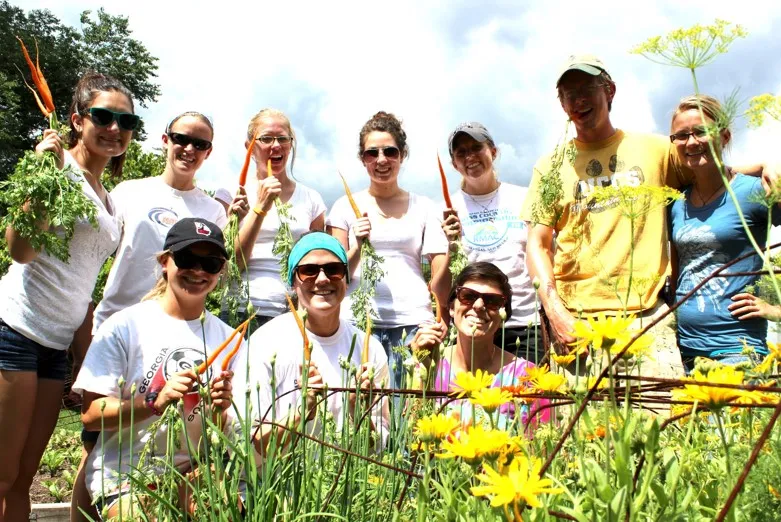 Group of students in a garden holding carrots