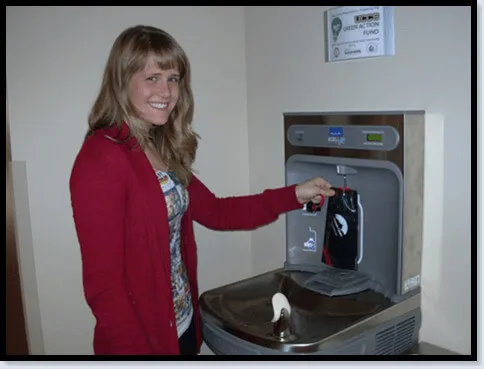 Student using the hydration station filler by putting her water bottle under the sensor