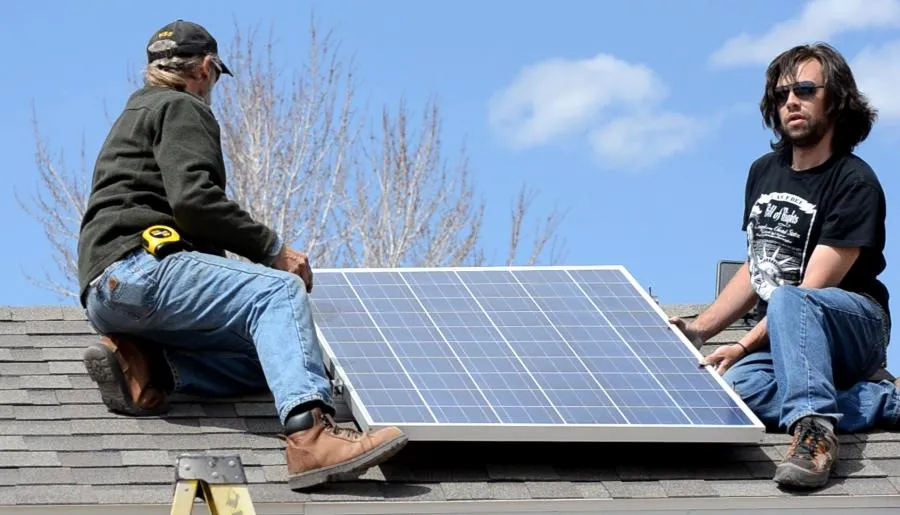 Two men installing a solar panel on a roof