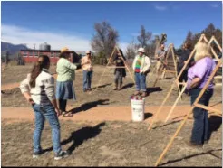 People standing on grass with wooden frames next to them.